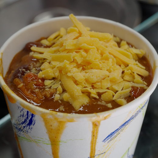 A cup of chili under shredded cheddar
